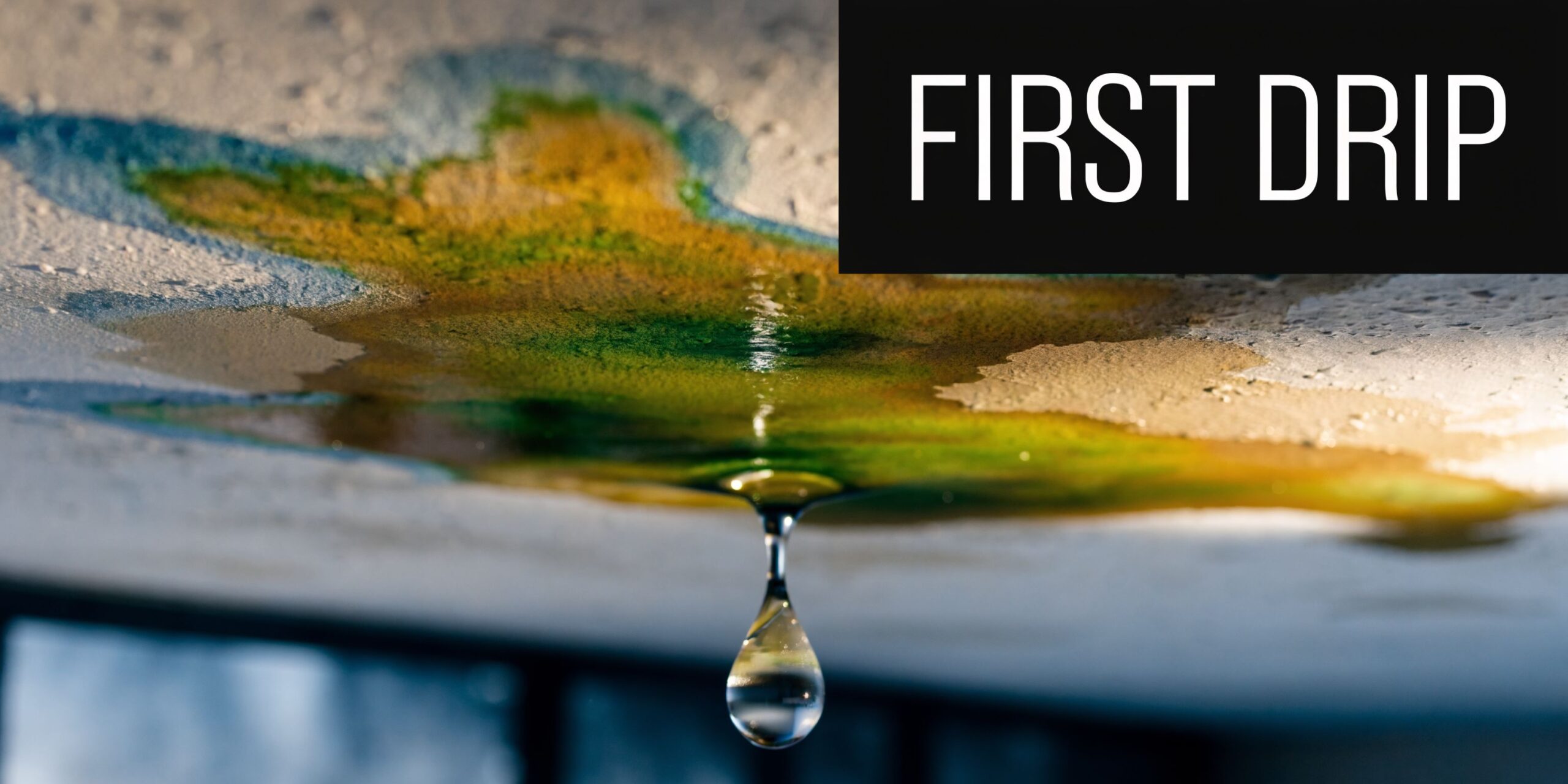 A water leak coming from a ceiling stained with yellow and green marks before the first drip.